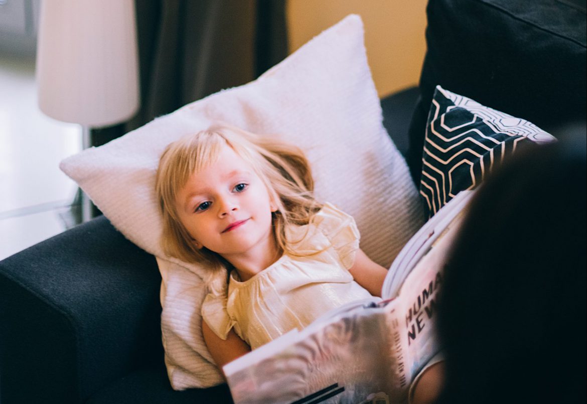 little-girl-with-magazine-looking-at-crop-unrecognizable-4187767